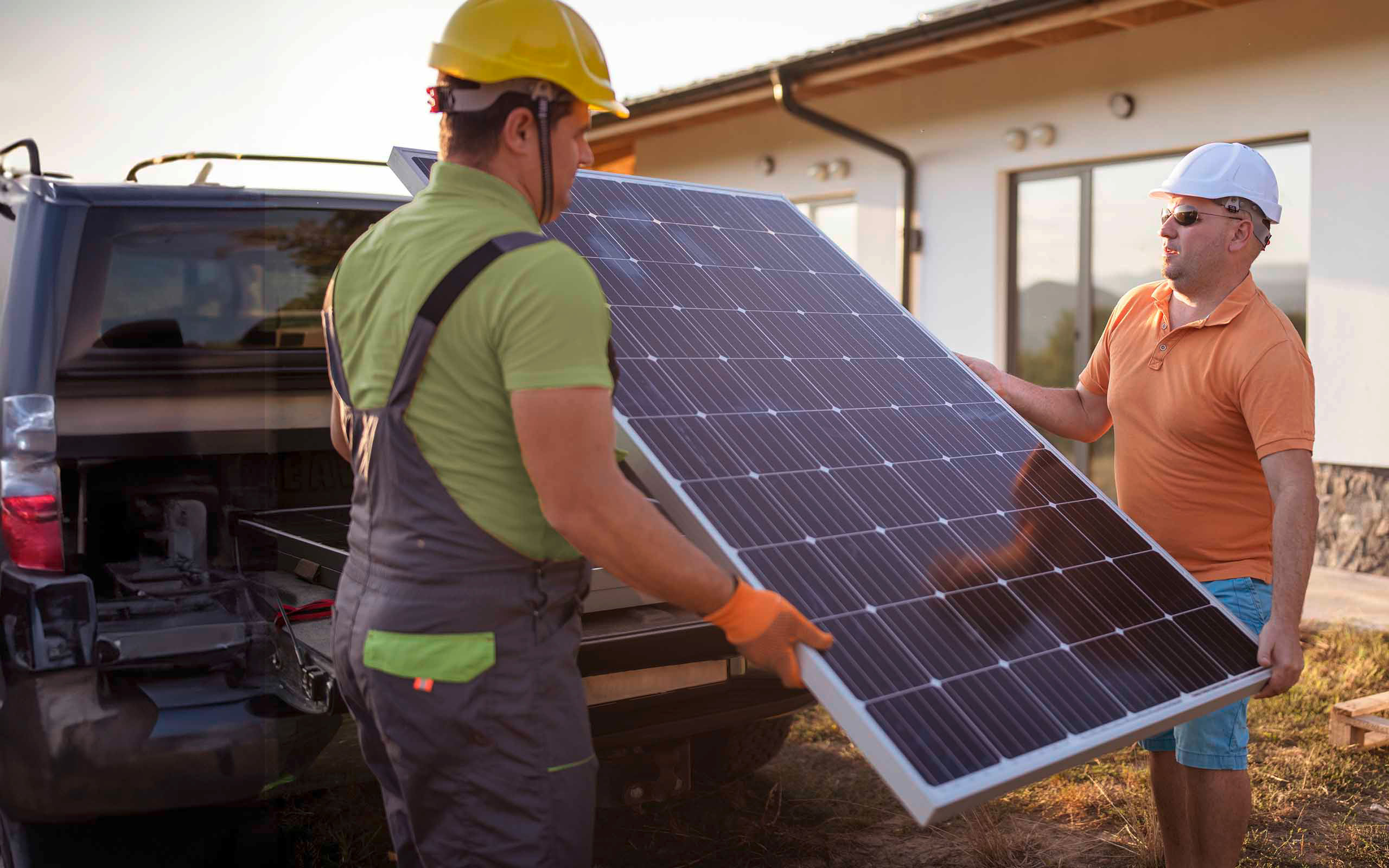 Zwei Männer entladen ein Photovoltaik-Modul von einem Transporter