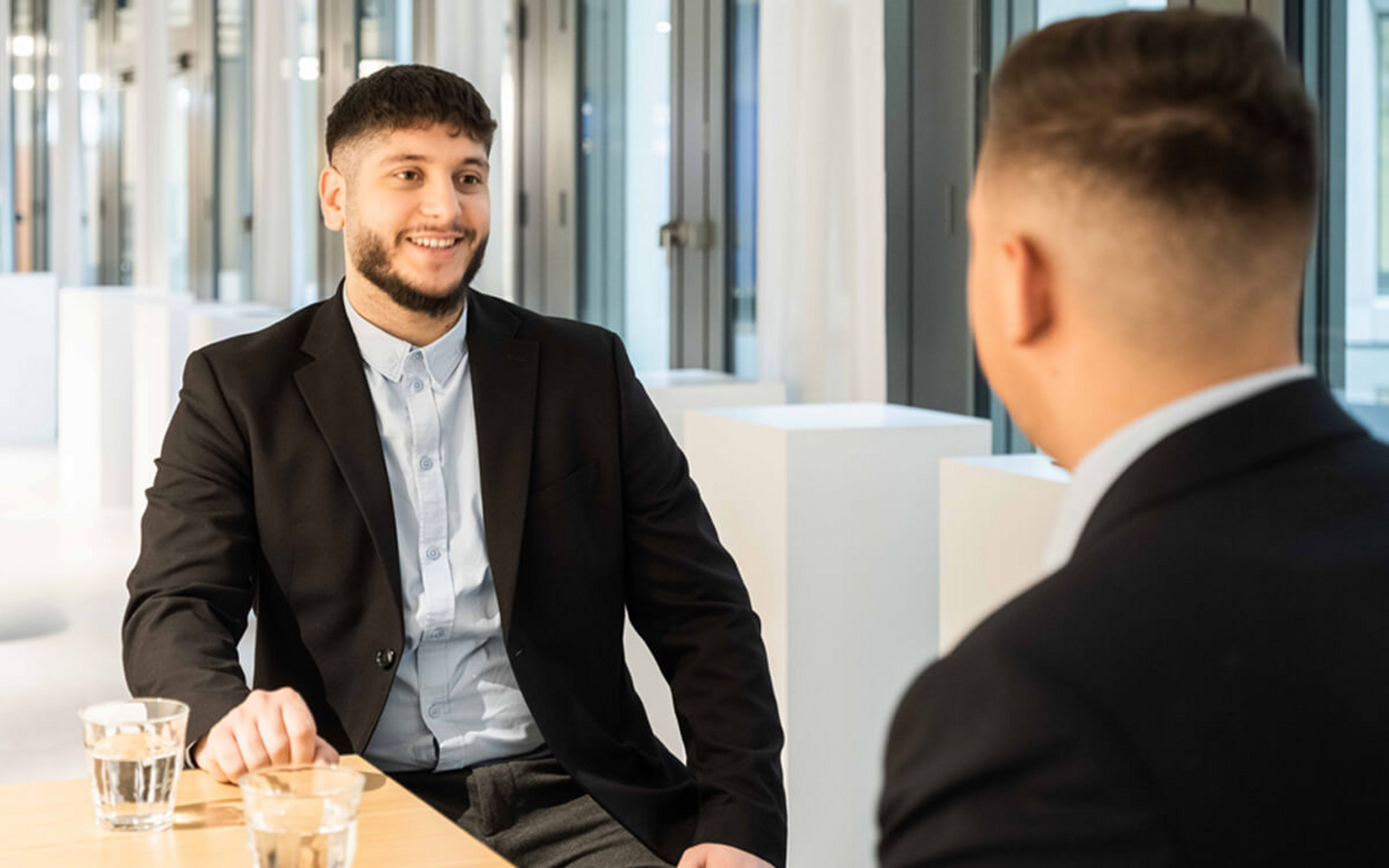 Zwei junge Männer sitzen an einem Tisch und sind im Gespräch