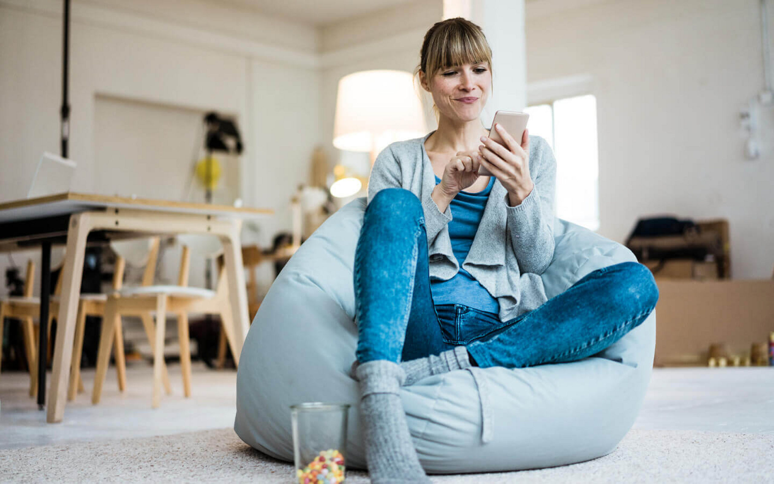 Eine Frau sitzt auf einem Sitzsack und bedient ihr Handy