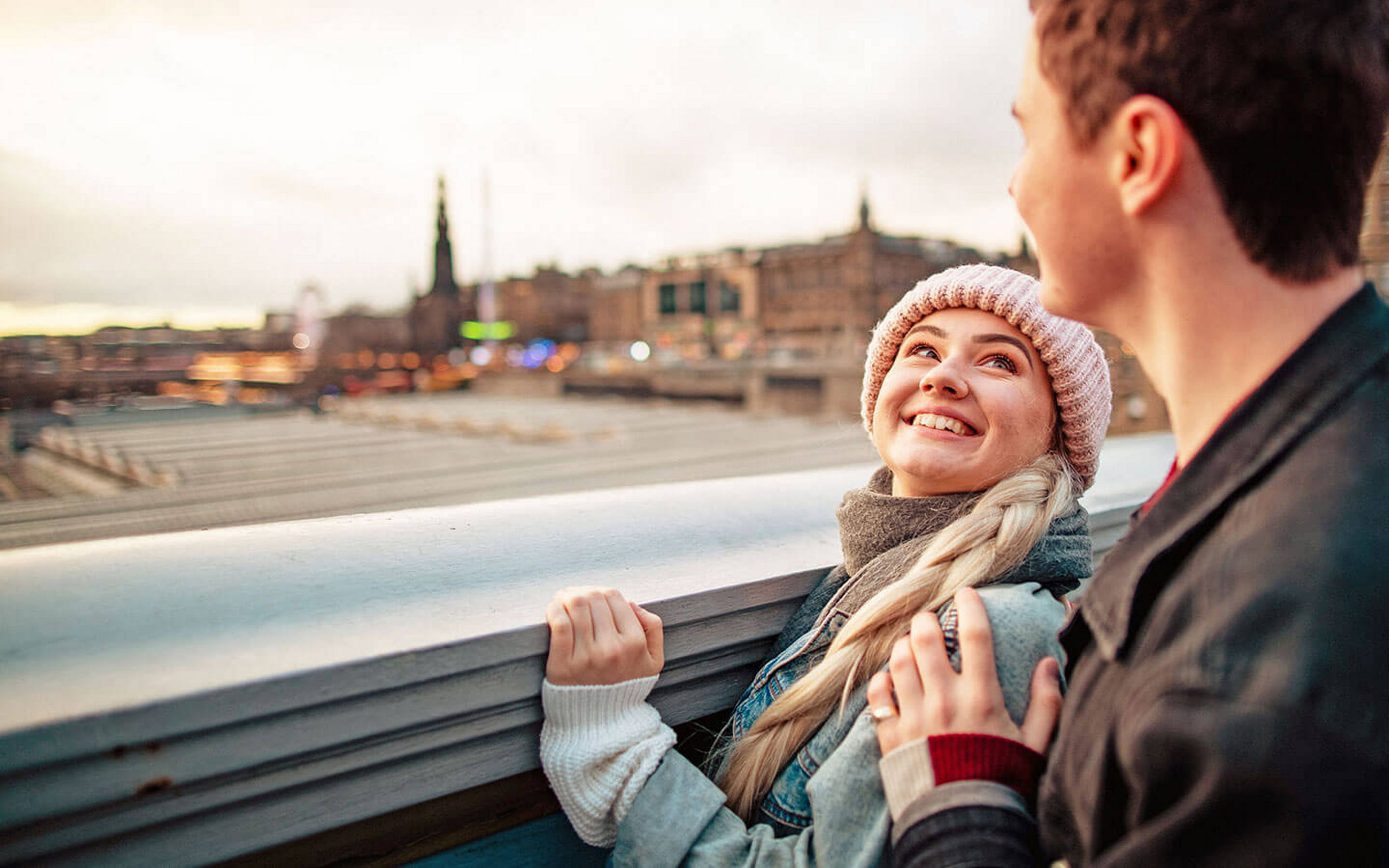 Ein Paar steht auf einer Brücke und sieht sich verliebt an