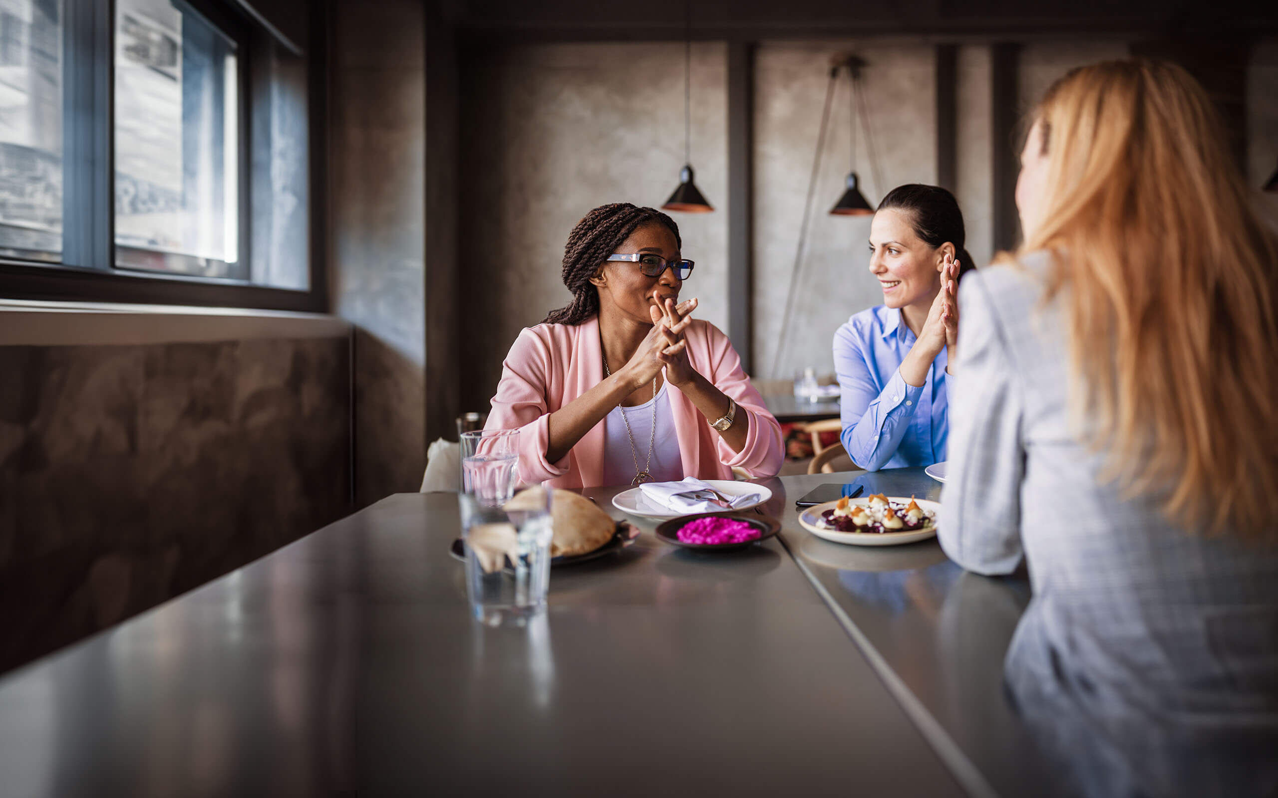 Drei Frauen sitzen in einem Café und unterhalten sich angeregt.