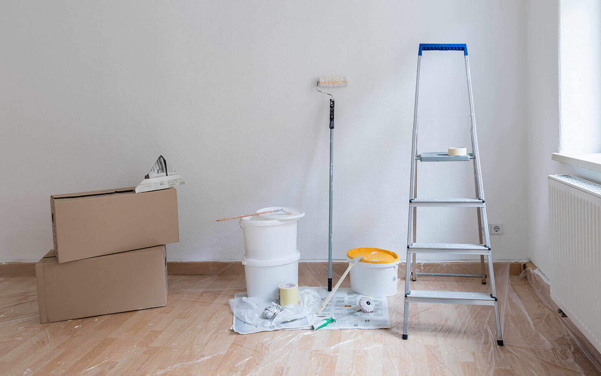 Eine Leiter und Malerutensilien stehen in einer leeren Wohnung