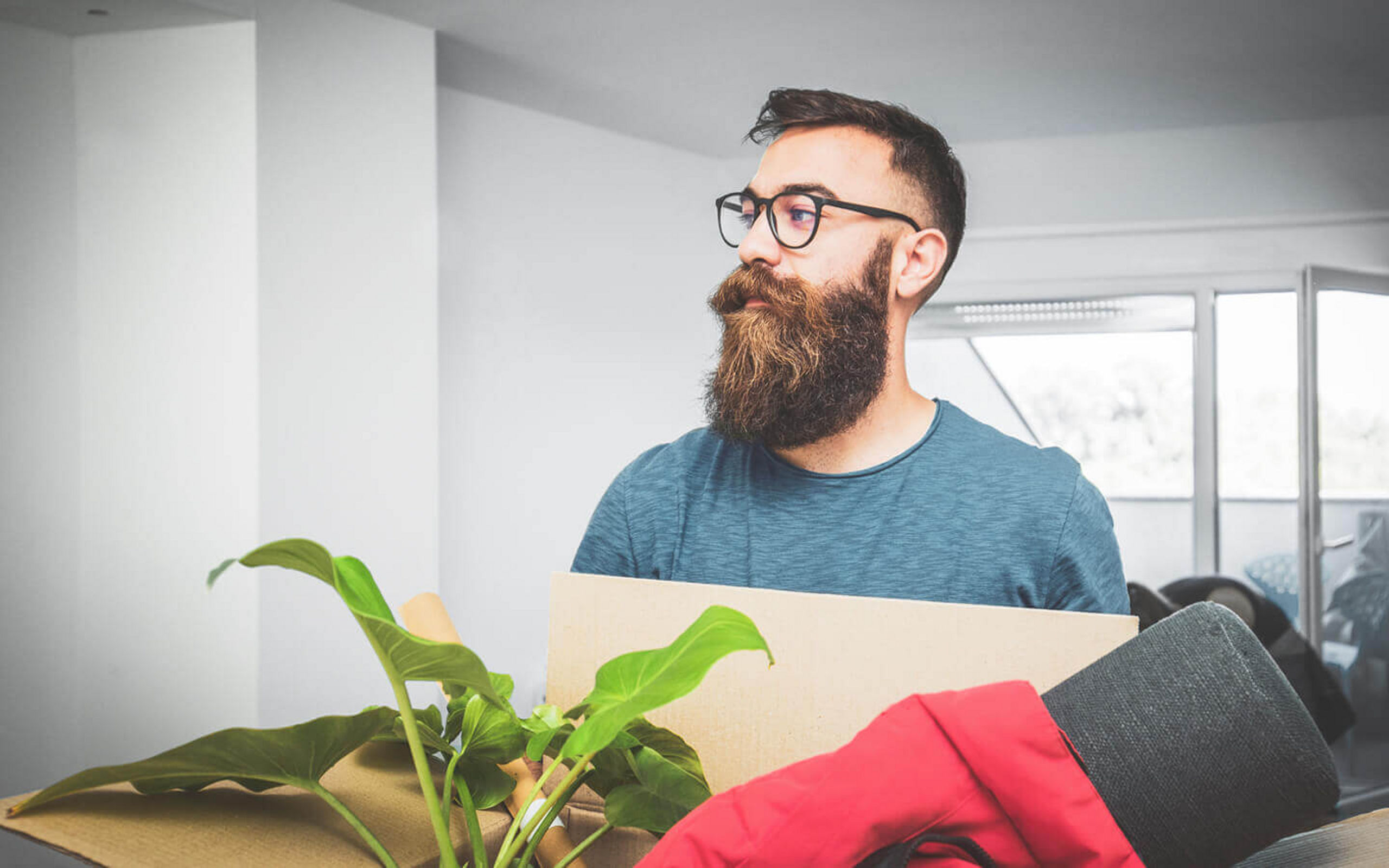 Eine junger Mann trägt eine gefüllte Umzugskiste