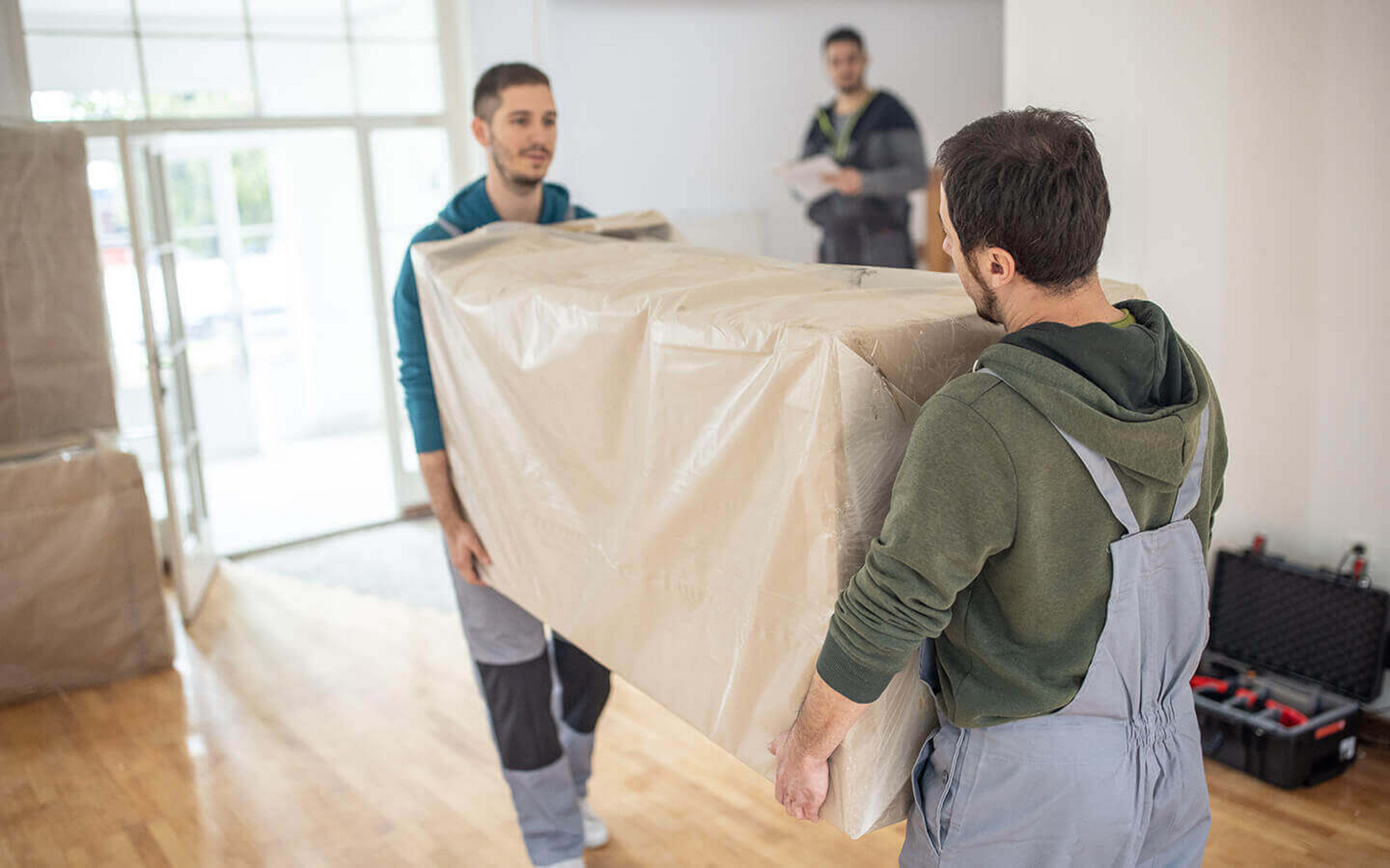 Zwei Möbelpacker tragen zusammen einen Schrank