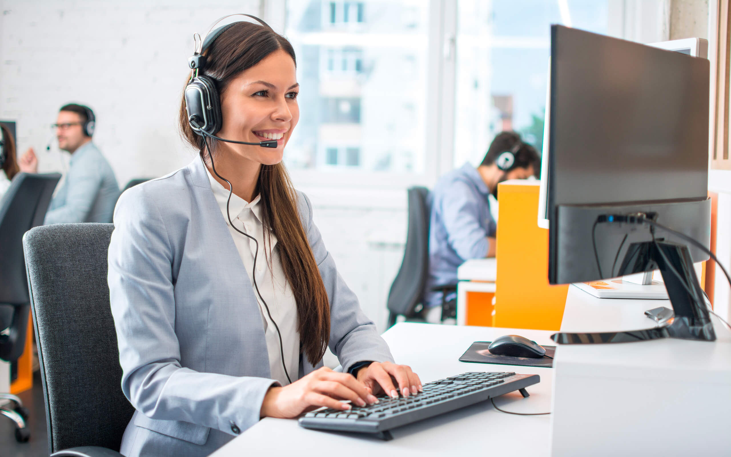 Eine Frau mit Headset sitzt an einem Computer