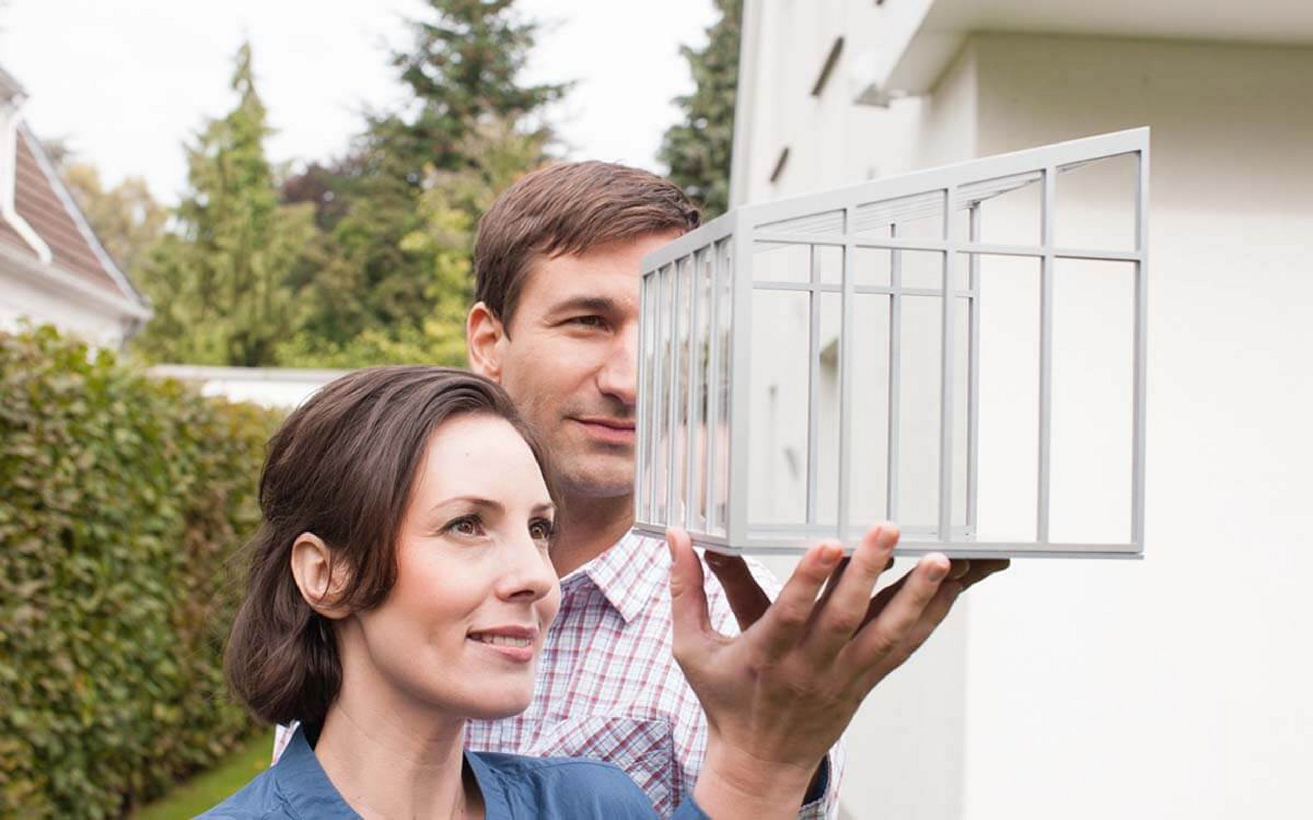 Eine Frau zeigt einem Mann ein Modell von einer Terrassenüberdachung