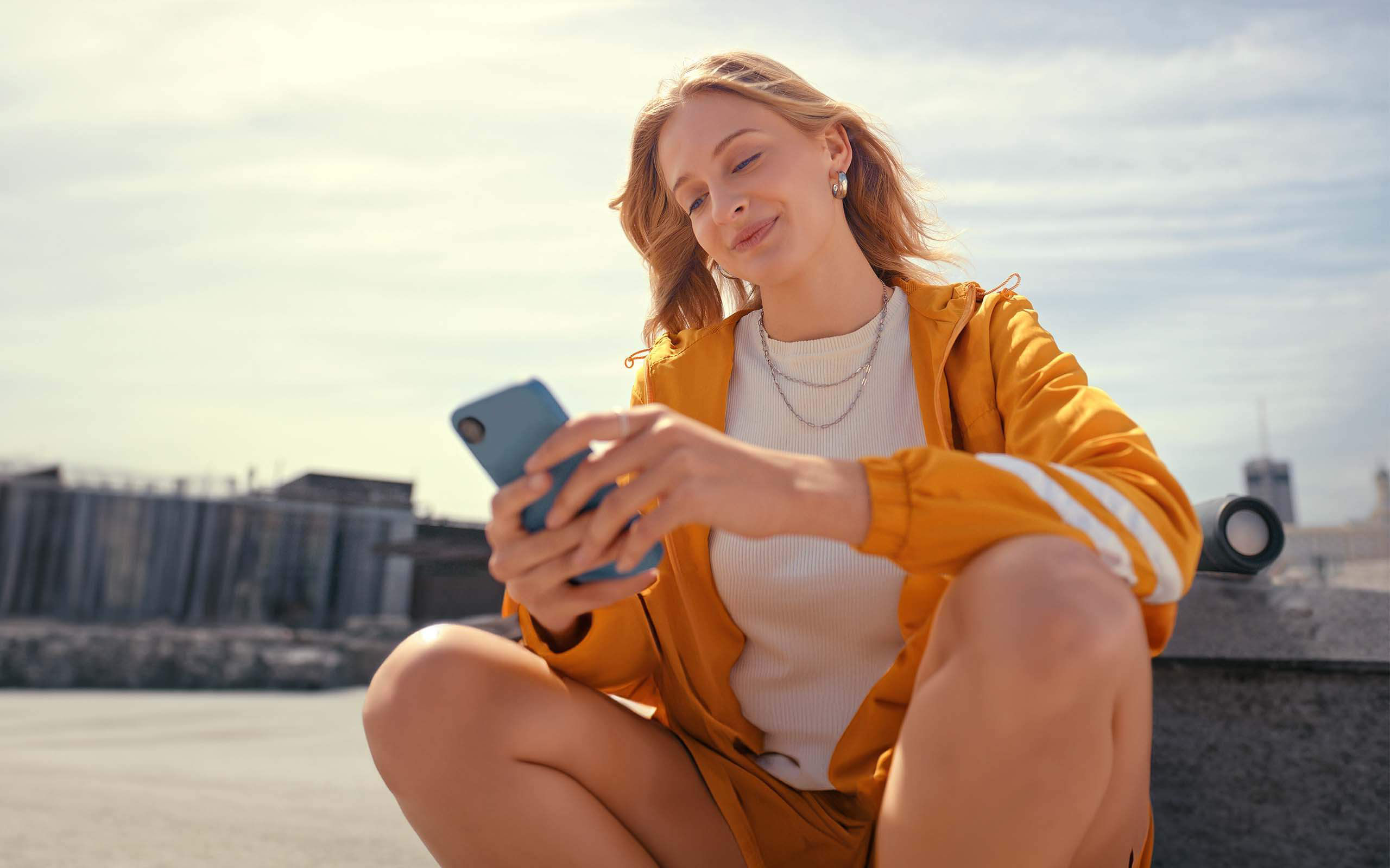 Eine Frau sitzt auf einem öffentlichen Platz und bedient ihr Smartphone