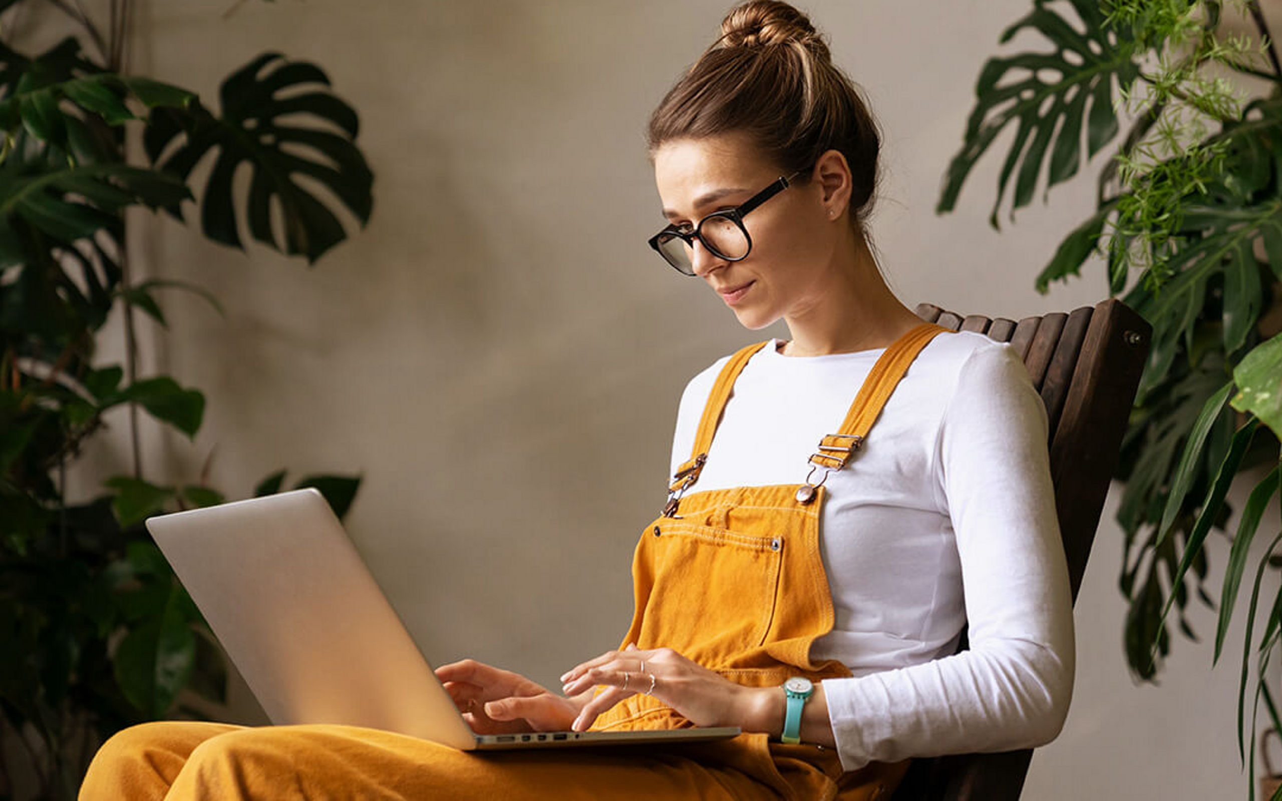 Eine junge Frau mit Brille mit Laptop auf dem Schoß