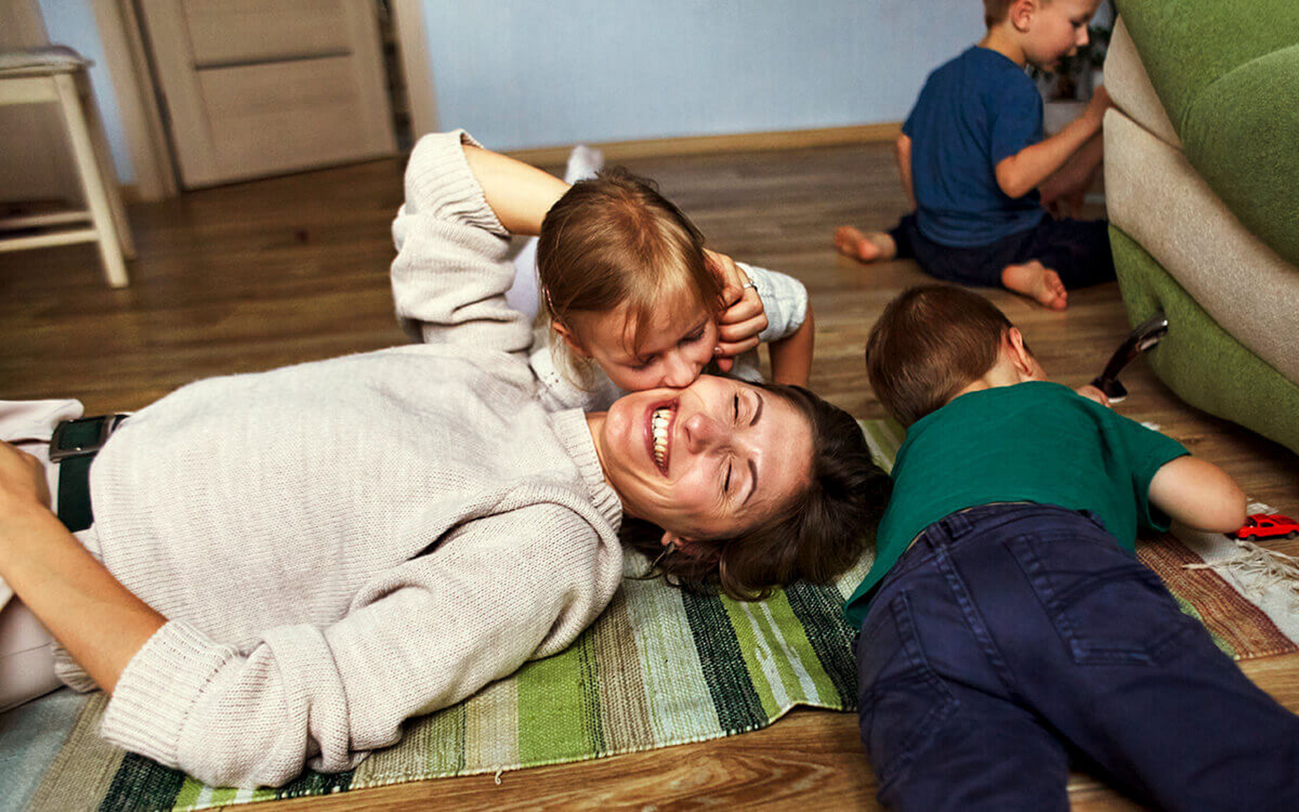 Eine junge Frau und drei Kindern toben auf dem Fußboden