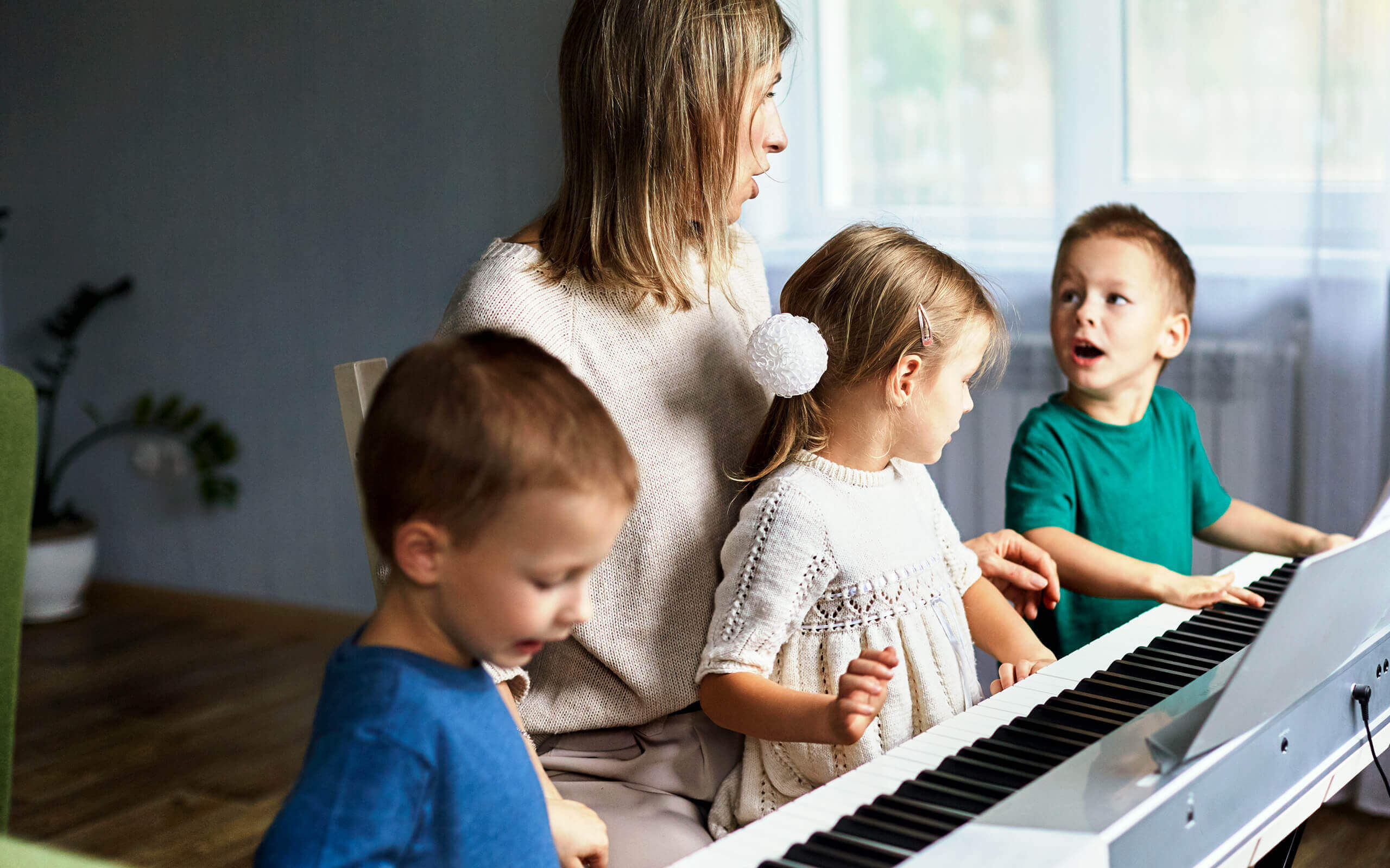 Eine junge Frau mit drei Kindern übt an einem elektronischen Klavier