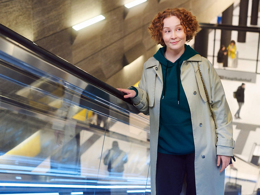 Eine Frau fährt auf einer Rolltreppe aus einer Haltestelle