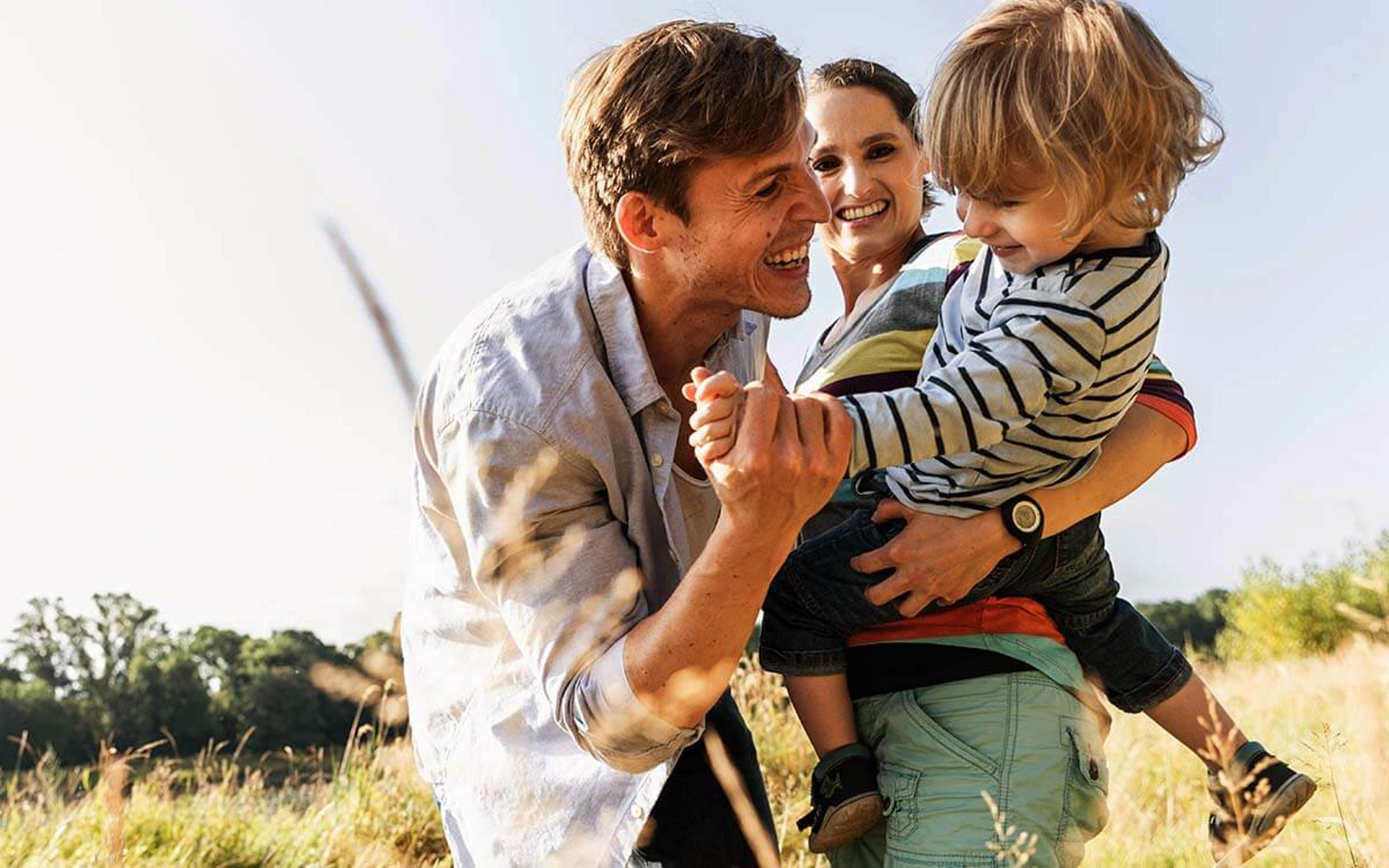 Ein Familie lacht und tobt auf einem Feld