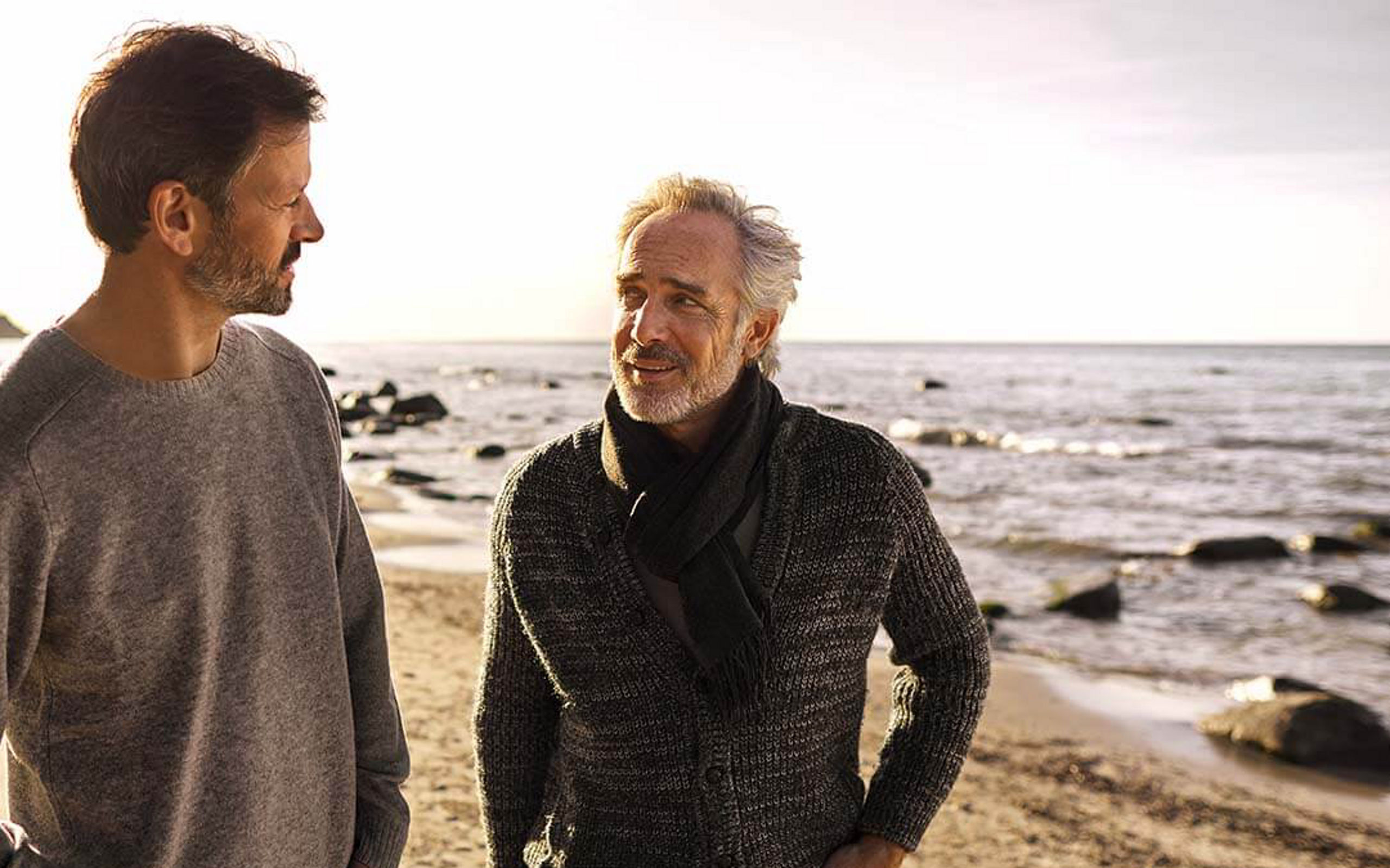 Ein Vater spricht mit seinem erwachsenen Sohn am Strand