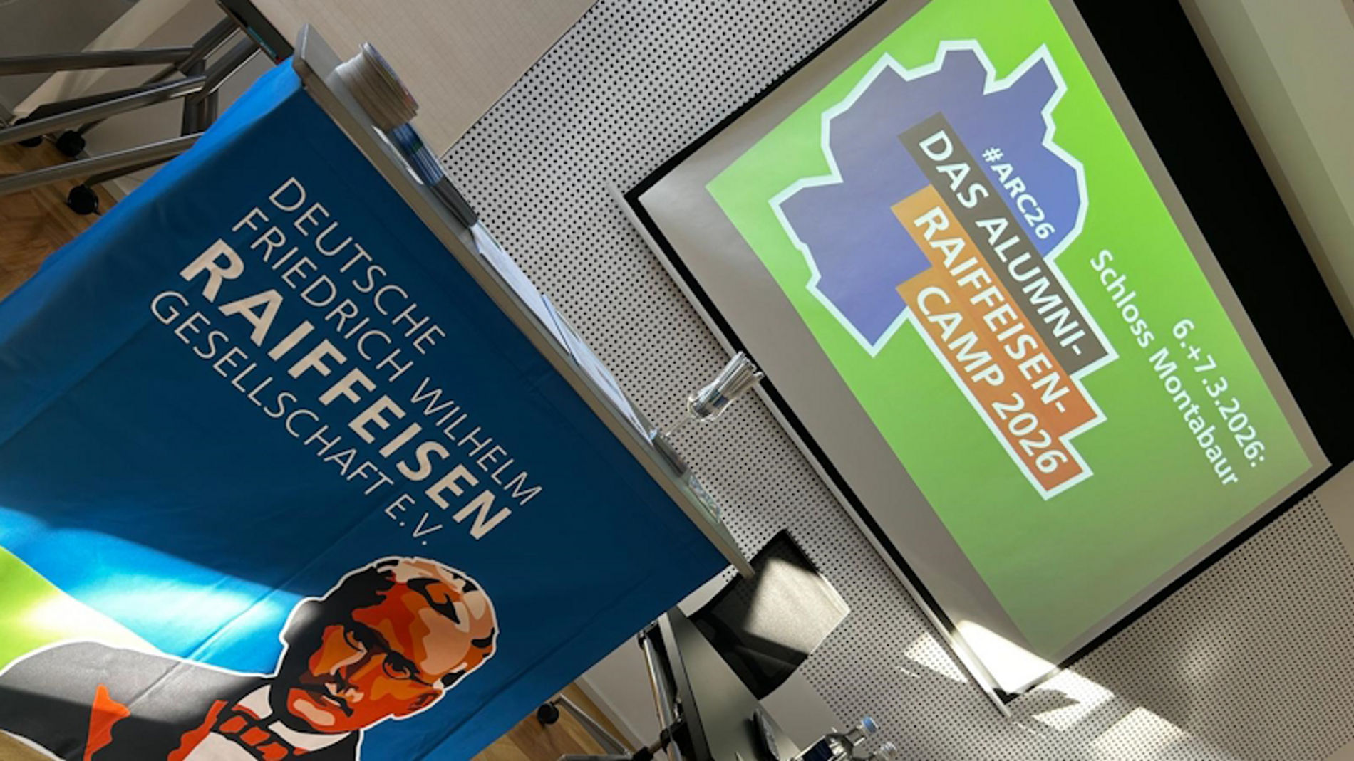Blick auf Rednerpult und Screen mit Logos