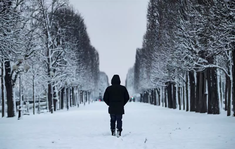 Una persona camina por París nevado.