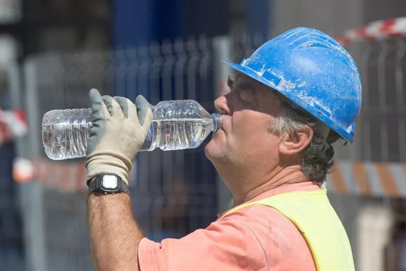 Eraikuntzako langile bat, ura edaten, bero handiko egun batean.