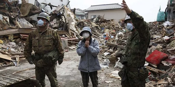 Una mujer y dos militares inspeccionando los daños de una casa. Foto: EFE