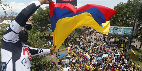 Un hombre ondea la bandera colombiana durante las protestas. Foto: EFE.