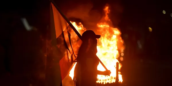 Una mujer camina con una bandera de Colombia durante una velatón en homenaje al joven Nicolás Guerrero. Foto: EFE.