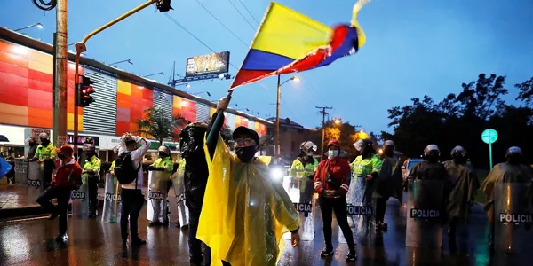 Un hombre ondea la bandera colombiana durante las protestas. Foto: EFE.