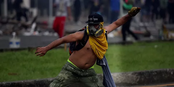 Un hombre lanzando objetos durante los disturbios. Foto: EFE.