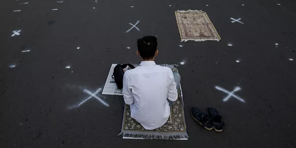 Un hombre sentado entre cruces que marcan las distancias. Foto: EFE.