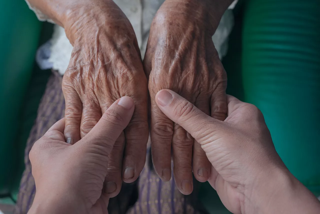 Alzheimerra gazte bat adineko bati eskuak heltzen. CC-BY www.freepik.es