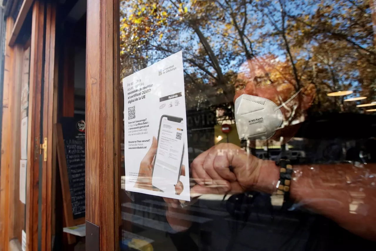 Un hostelero cuelga el cartel de obligatoriedad de pasaporte covid en Cataluña
