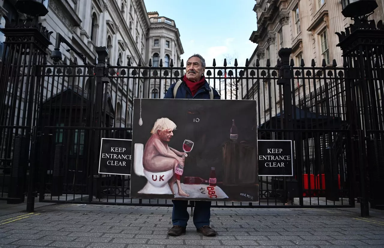 El artista Kaya Mar posa con una de sus obras frente a Downing Street. Foto: EFE