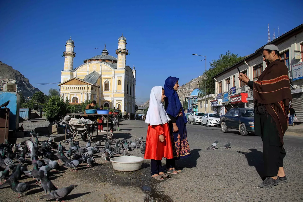 Gizon bat bi neskari argazkia ateratzen maiatzaren 1ean, Eid al-Fitr jaian. Argazkia: EFE