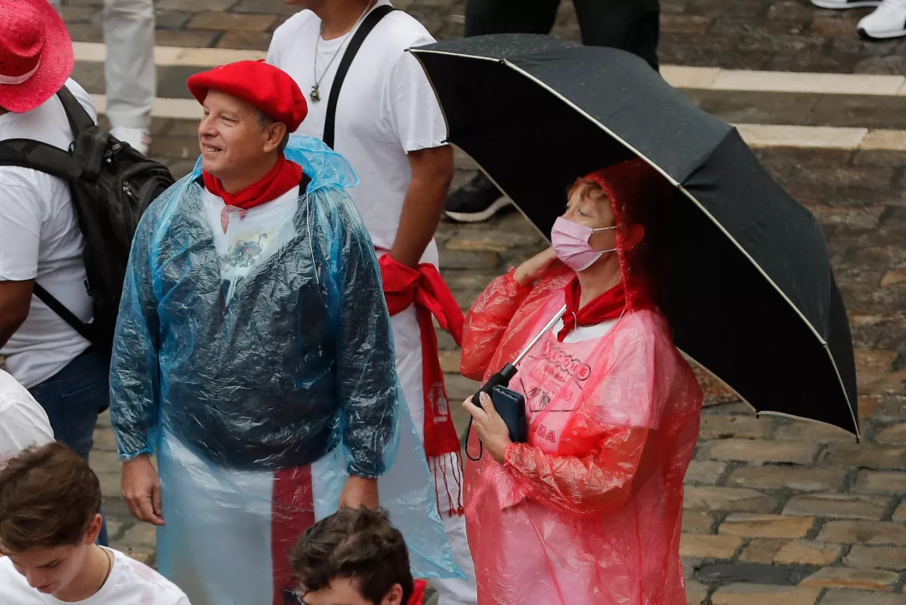 Una mujer espera al chupinazo con un paraguas. Foto: EFE.