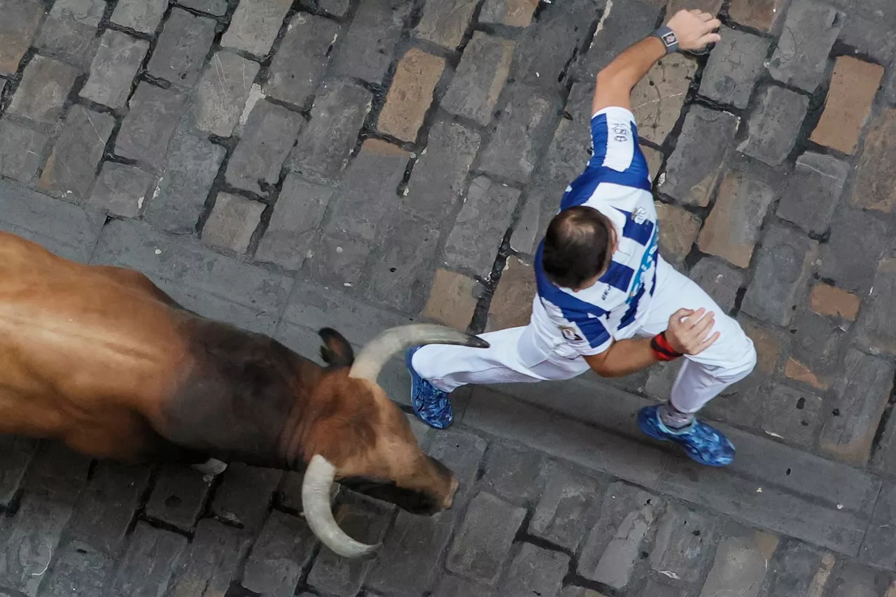 Un corredor corre con un toro detrás.