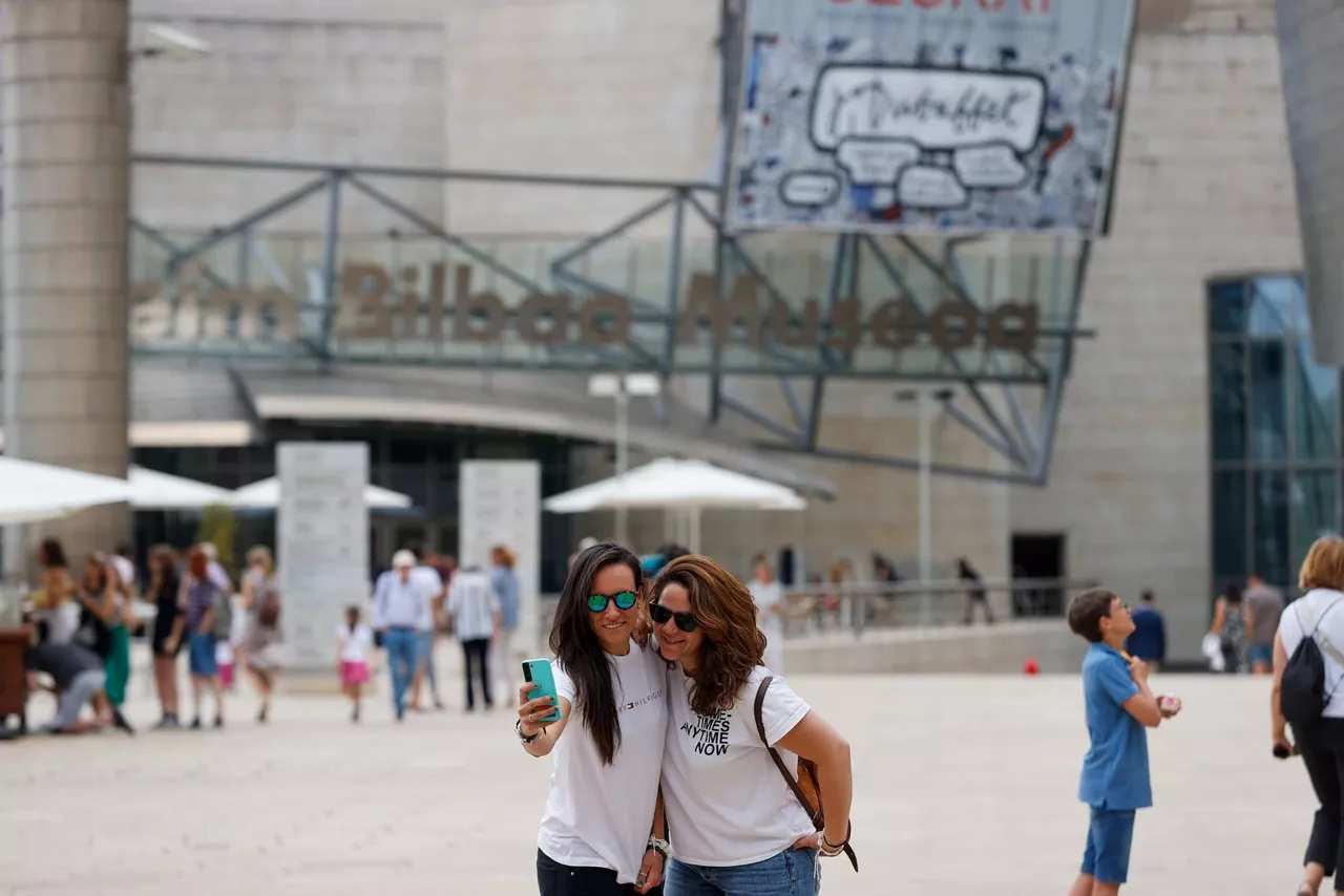Dos turistas se fotografían en Bilbao, este verano.
