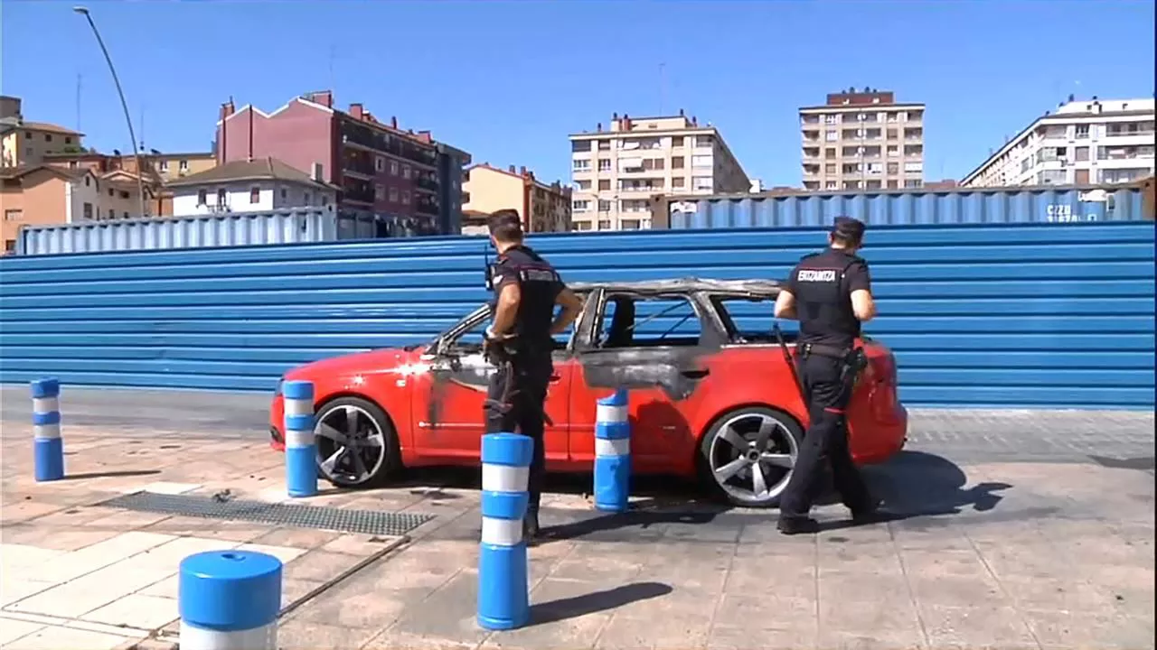 Dos ertzainas observan el vehículo quemado por el encarcelado en Pasaia. Imagen: EITB Media