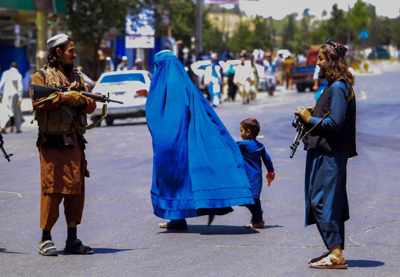 Una mujer cruza la calle en Kabul ante la mirada de dos hombres armados