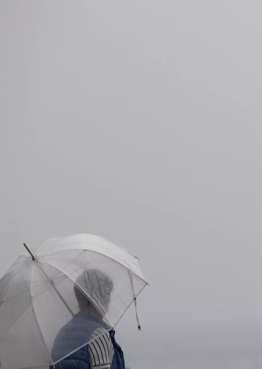 Una mujer, bajo el paraguas, en Donostia. Foto: EFE