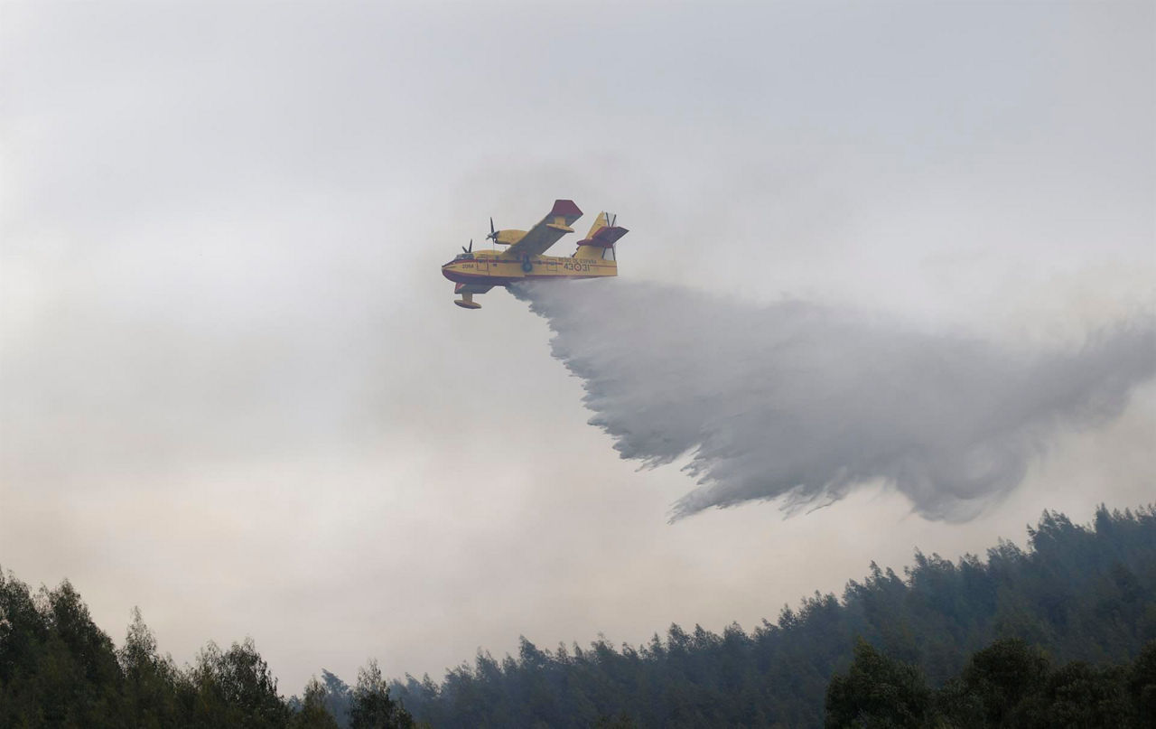 Un avión anfibio descargando agua en el incendio de Berango. Foto: EFE