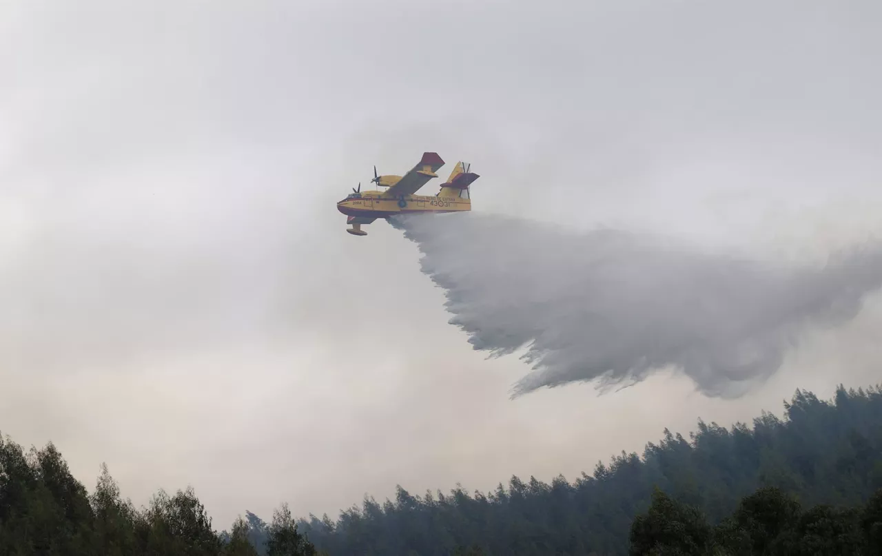 Un avión anfibio descargando agua en el incendio de Berango. Foto: EFE