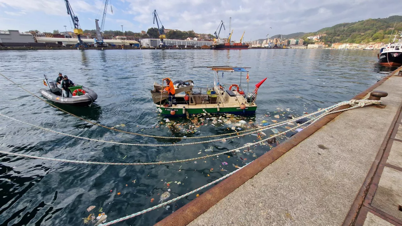 Operarios recogen la basura vertida al agua.