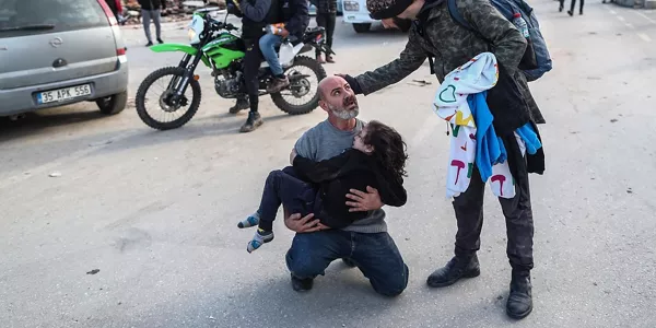 Un hombre con una menor en brazos en Hatay (Turquía). Foto: EFE