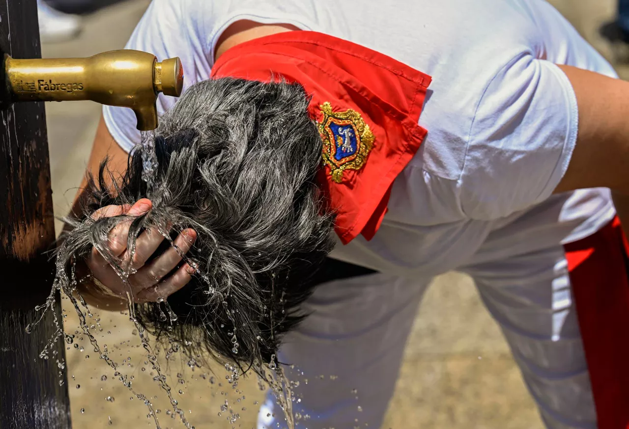 Emakume bat Gazteluko plazako iturri batean freskatzen, Iruñean. Argazkia: EFE