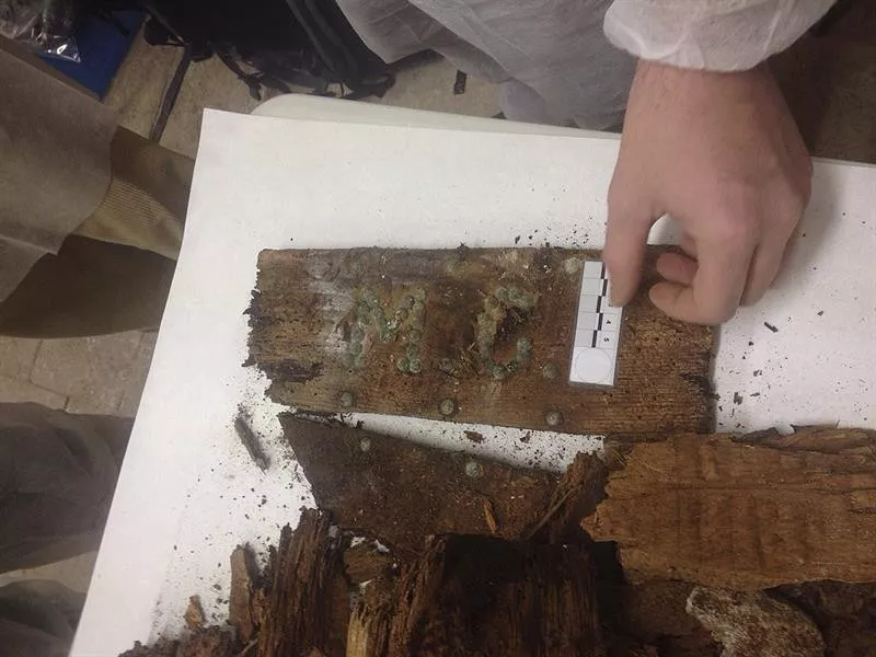 Tabla de madera con las iniciales hallada por los investigadores. Foto: EFE