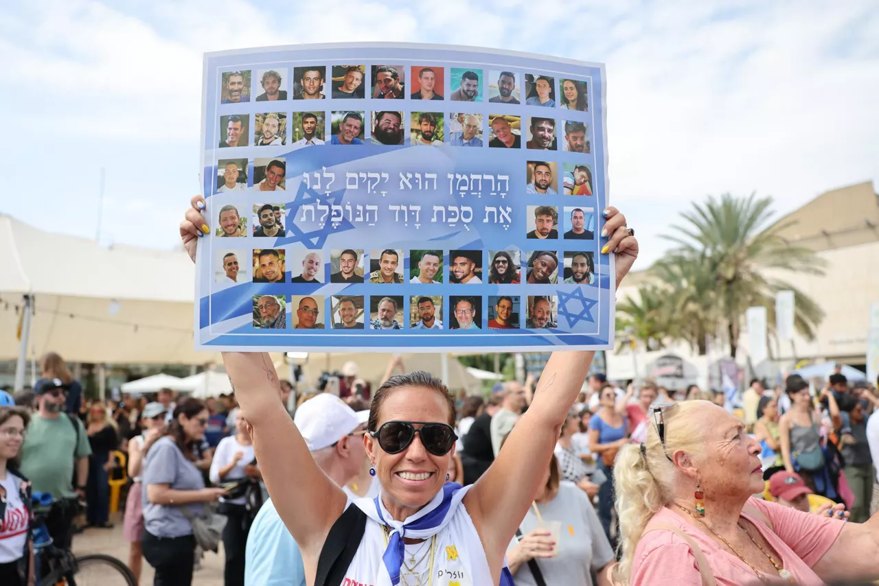 tel aviv (Israel), 09/10/2025.- A woman holds a placard with photos of Israeli hostages that reads in Hebrew, 'The Merciful One will raise up for us the fallen tabernacle of David,' during a celebration after a peace deal is announced at Hostages Square in Tel Aviv, Israel, 09 October 2025. US President Donald Trump announced that Israel and Hamas have agreed to the first phase of a Gaza peace plan. The deal involves the release of Israeli hostages and Palestinian prisoners, the withdrawal of Israeli forces, and the delivery of humanitarian aid to Gaza. EFE/EPA/ABIR SULTAN
