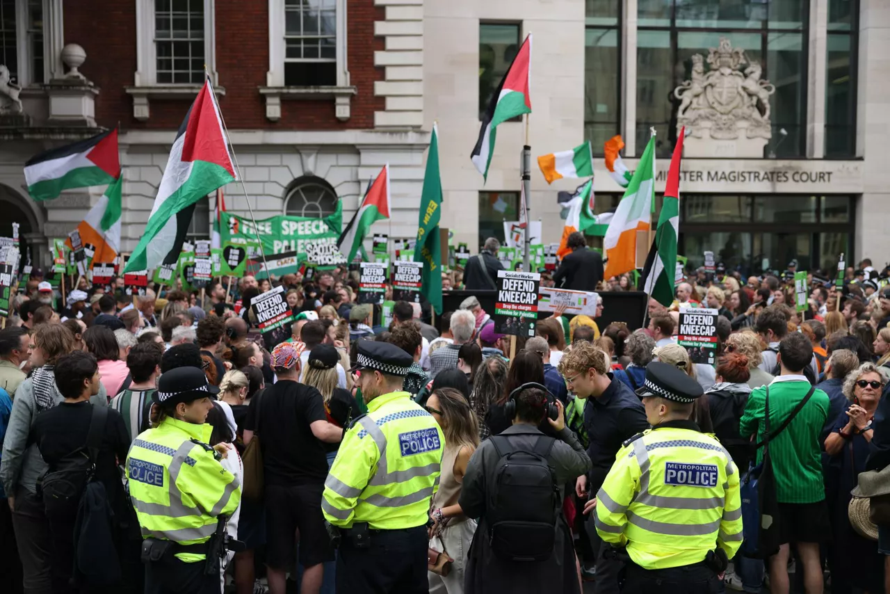 LONDON (United Kingdom), 20/08/2025.- Police Officers watch as supporters of Kneecap's Liam O'Hanna wave Palestinian flags outside Westminster Magistrates' Court ahead of his appearance in court in London, Britain, 20 August 2025. The musician, known as Mo Chara and also as Liam Og O hAnnaidh, appeared in court on a terrorism charge for displaying a Hezbollah flag at a November 2024 gig. (Terrorismo, Reino Unido, Londres, Hizbulá/Hezbolá) EFE/EPA/NEIL HALL
