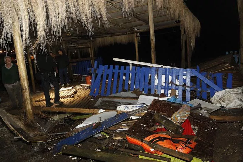 Un bombero chileno pasa al lado de varios destrozos causados por una ola en Con Con. Foto: EFE