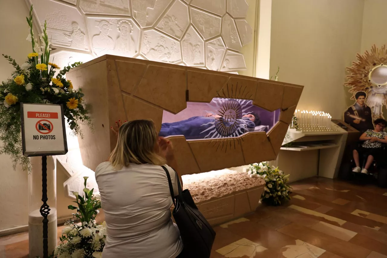 Assisi (Italy), 07/09/2025.- A faithful looks at the body of Saint Carlo Acutis at the Sanctuary of the Renunciation in Assisi, Italy, 07 September 2025. Carlo Acutis, an Italian teenager who died in 2006, will be canonized by Pope Leo XIV in a ceremony at the Vatican, becoming the first millennial saint. (Papa, Italia) EFE/EPA/GIANLUIGI BASILIETTI
