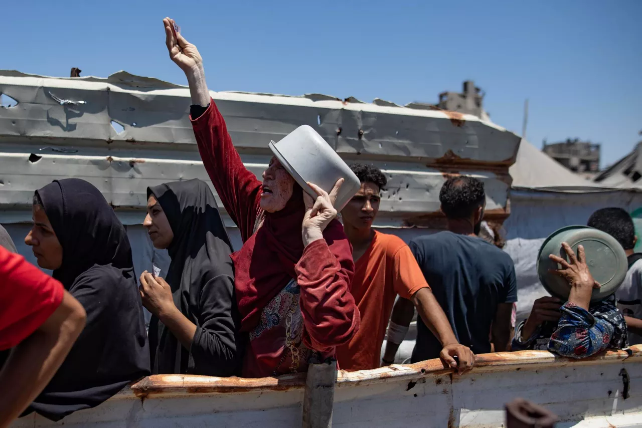 Pertsona batzuk Gazan janaria jasotzeko txandaren zain daude. Argazkia: EFE