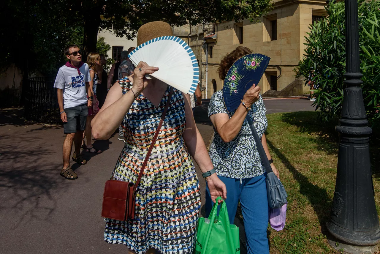 BILBAO, 15/08/2025.- Dos mujeres se protegen del sol con sus abanicos, este viernes en Bilbao, donde han decretado alerta naranja por altas temperaturas. Numerosas localidades de Euskadi han registrado una nueva noche tropical, con mínimas que no han bajado de los 20 grados, que augura una jornada que desde la Agencia Vasca de Meteorología-Euskalmet prevén que pueda ser la más calurosa del verano en la comunidad autónoma. EFE/ Javier Zorrilla
