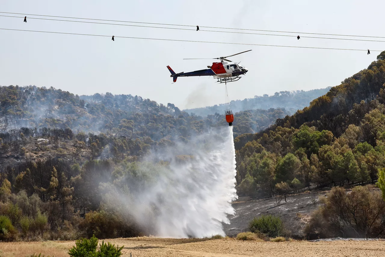 A firefighting helicopter cools down the burnt area by the fire that has been burning since last Saturday night in a forest area in the municipality of Carcastillo (Navarra), Spain, 11 August 2025, the fire remains uncontrolled. EFE/ Jesus Diges
