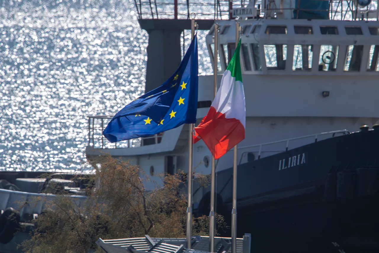 (Foto de ARCHIVO)

La banderas europea e italiana ondean en el centro de migrantes en el puerto de Shëgjin, a 22 de octubre de 2024, en Shengjin (Albania). Este recinto es uno de los dos centros construidos por el Gobierno italiano en Albania para recibir a los solicitantes de asilo rescatados en el Mediterráneo. El pasado 16 de octubre llegó el primer buque militar fletado por Italia al centro de Shegjin con 16 migrantes a bordo, aunque todos ellos han sido devueltos a Italia después de que la Judicatura italiana ordenó su retorno al considerarse que la procedencia de los migrantes, Bangladesh y Egipto, no puede considerarse segura.



Antonio Sempere / Europa Press

22 OCTUBRE 2024;MIGRANTES;INMIGRANTES;

22/10/2024